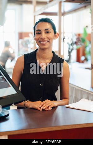 Portrait of smiling female receptionist at shared workspace front desk Stock Photo