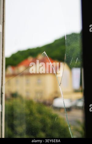 Broken glass in a window frame with visible crack and shattered fragment, symbolizing home damage, accident, burglary or security risk. Stock Photo