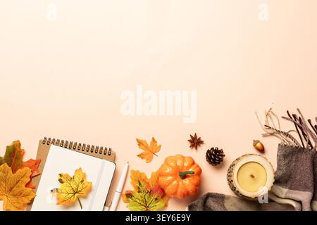 Autumn flat lay background. Autumn leaves, notepad, scarf, candle and spices on yellow background. Stock Photo