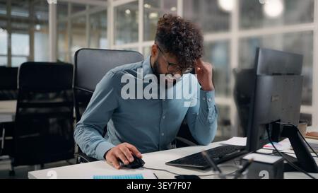 Tired exhausted Arabian ethnic business man working with computer sad suffering with headache problem painful hurt upset stressed businessman work Stock Photo