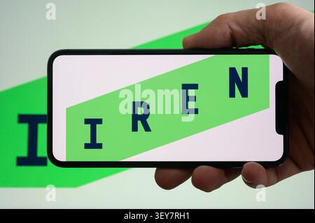 Paris, France - July 2, 2026: A hand holding a smartphone displaying the Iren company logo on a white and green background. Stock Photo
