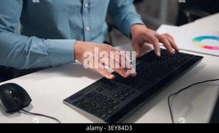 Close up male hands typing keyboard unrecognizable business man using computer at table in company managing work colorful diagram paper document stats Stock Photo