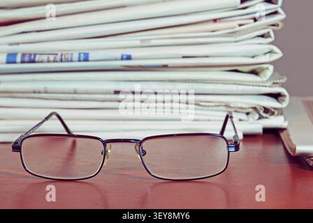reading glasses and folded newspapers on the desk Stock Photo