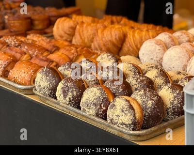 Assorted pastries on display at bakery counter, featuring chocolate-covered and sugar-dusted treats. Mobile photo Stock Photo