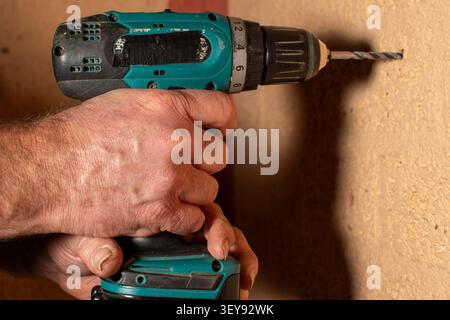 Hand holding a cordless drill while working, close‑up shot showing the tool and manual action. Stock Photo