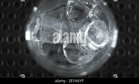 Ice cubes chilling in a glass from overhead view, refreshing cold drink on dark background Stock Photo