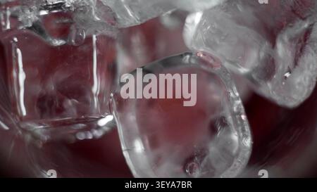 Ice cubes melting in a refreshing red drink, creating bubbles and a cooling liquid effect, close-up macro view Stock Photo