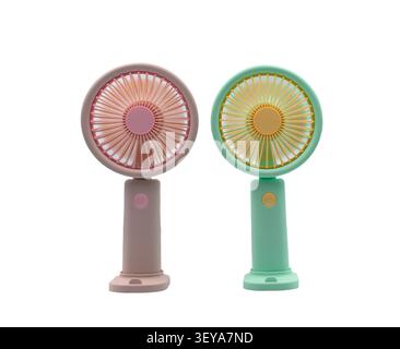 Two portable handheld fans in pastel pink and green on a white background, for cooling off on hot summer days. Stock Photo