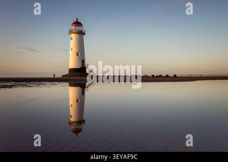 Perfectly still low-tide pool reflecting the iconic silhouette of the Point of Ayr Lighthouse on Talacre Beach at twilight Stock Photo