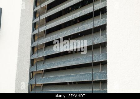 Window shutters made of durable materials are installed on the exterior of a modern residential building. The shutters allow for ventilation while maintaining privacy and aesthetics. Stock Photo