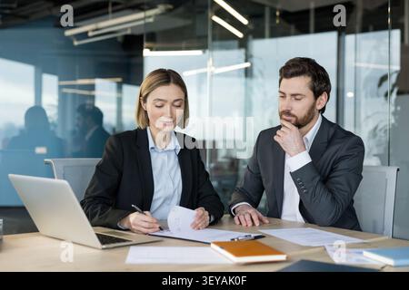 Business associates collaborating on financial documents and reports in a modern office meeting, discussing strategies and analyzing data for corporate growth and successful project management Stock Photo