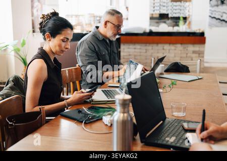 Businesswoman using smart phone during her work session at shared workspace Stock Photo