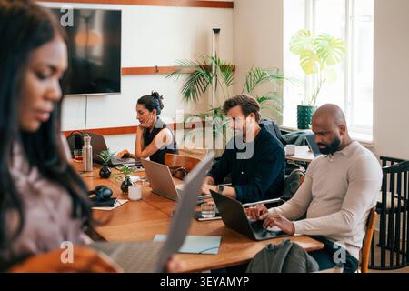 Friendly corporate team working on laptops at shared workspace Stock Photo
