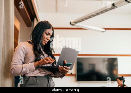 Focused businesswoman working on laptop at modern coworking space Stock Photo