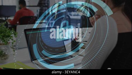 Female employee watching laptop code, laptop sending cybersecurity HUD with padlock scanning desk Stock Photo