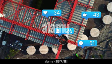 Drone capturing large red steel truss spanning tank farm, showing rising blue icons Stock Photo