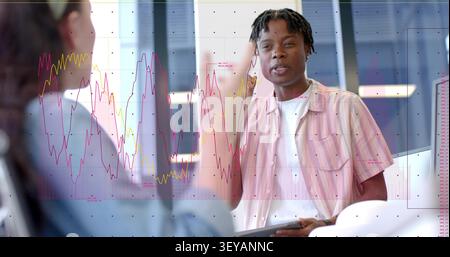 Man with tablet checking data and replying after woman gesturing, charts dotted grid overlaying IT Stock Photo