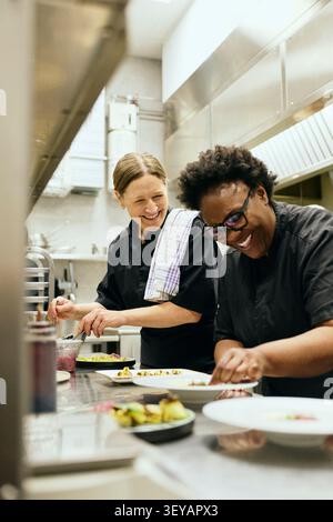 Happy female chefs talking with each other while working in commercial kitchen Stock Photo