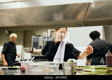 Group of happy chefs communicating with each other while working in busy restaurant kitchen Stock Photo