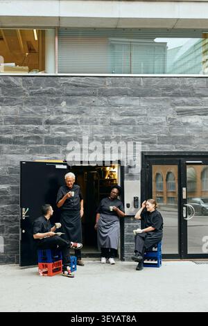 Group of kitchen staff taking coffee break outside restaurant building Stock Photo