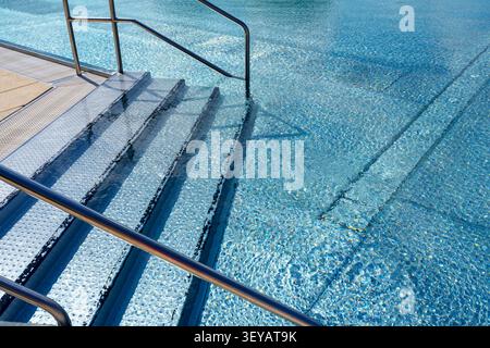 Metal steps and handrails in outdoor swimming pool Stock Photo