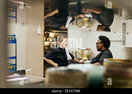 Two female chefs chatting during their shift in restaurant kitchen Stock Photo