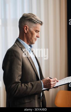 Senior businessman going through paperwork and documents at office Stock Photo