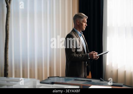 Thoughtful senior male entrepreneur holding documents at office Stock Photo