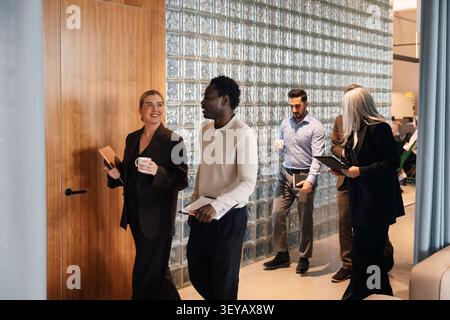 Group of diverse business colleagues walking and talking in office hallway Stock Photo