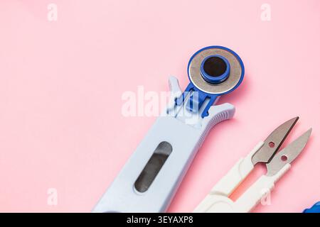 Minimal flat lay featuring a rotary cutter and thread snips on a soft pink background with ample copy space for creative projects, tailoring essential Stock Photo