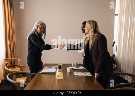Senior businesswoman shaking hand with clients after successful meeting Stock Photo