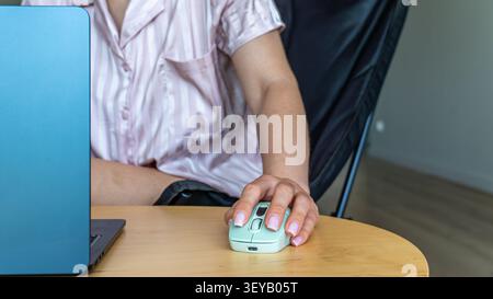 Close up of female hand using wireless computer mouse while working on laptop Stock Photo