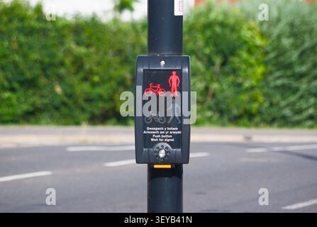 Bilingual pedestrian and cyclist crossing push button with illuminated no crossing symbol, UK street traffic control system Stock Photo