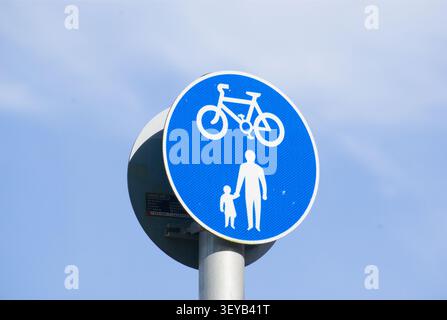 UK signpost advising people walking and cycling sharing the footpath in a blue circle with a blue cloudy sky in the background Stock Photo