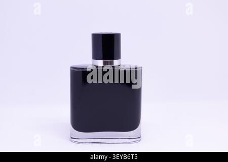 A black glass bottle stands on a white surface. It is designed for cosmetic products. The simple shape shows a modern style for beauty storage. Stock Photo