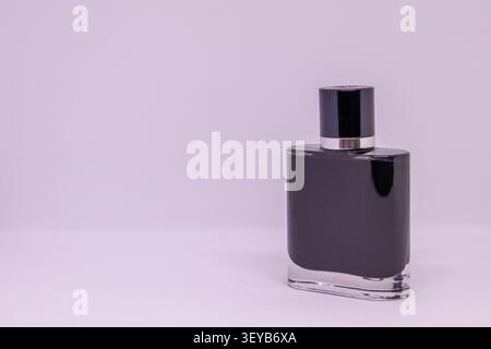 A black cosmetic bottle stands on a light surface. The bottle has a simple design, appearing sleek and modern. The cap is shiny and contrasts with the Stock Photo