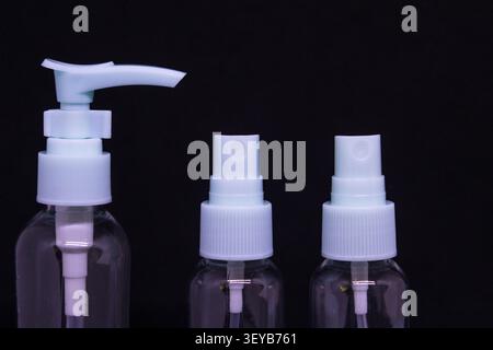 Three empty transparent plastic bottles with different tops are displayed against a black background. The bottles are arranged side by side in a neat Stock Photo