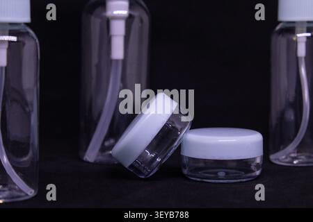 Three clear plastic bottles with a pump and spray top are placed together on a black surface. They are empty and ready for use in various tasks. Stock Photo