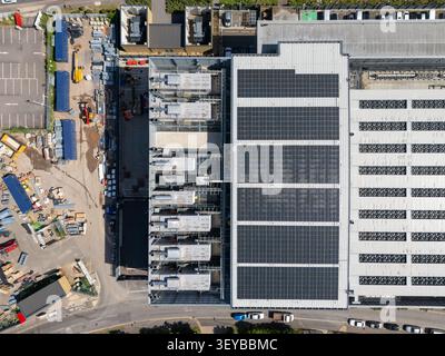 Aerial view of a datacenter fitout featuring rooftop solar panels and industrial HVAC units, surrounded by construction equipment and parking areas in Stock Photo