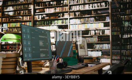 Dashboard presentation with blue screen and chatbot on computer monitors at wooden library desk with stack of books, headphones, keyboards and green lamps. Empty workspace. Stock Photo