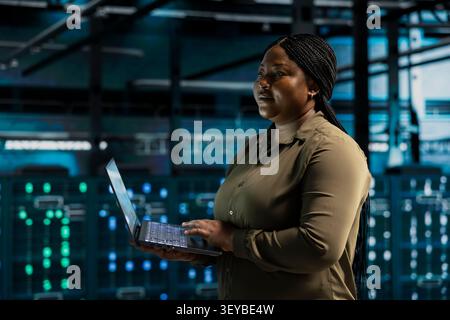 Data center engineer uses a digital device in a data center to run hardware diagnostics and maintain operational stability. Stock Photo