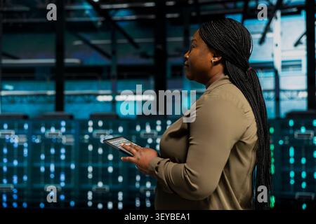 Software engineer working with device to do maintenance in server facility with setup helping companies stay connected. Stock Photo