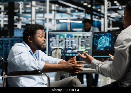 Engineer with disability and manager inspect a neural network data center, optimizing an inclusive server hub for AI workloads. Stock Photo