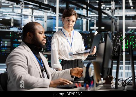 Data center team works together on diagnostics, maintenance tasks and server equipment performance checks. Stock Photo