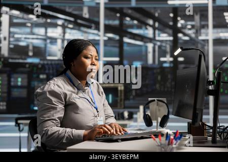 Server facility software engineer works with workstation to update servers tech, setting up equipment working with program. Stock Photo