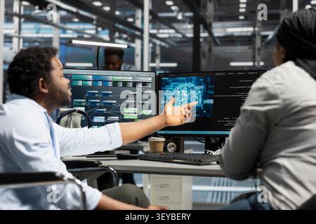 Data center engineer using a wheelchair uses a computer to manage machine learning workloads, working with AI technology and high performance systems. Stock Photo