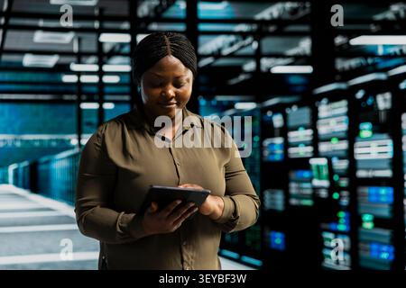 Positive data center administrator works confidently in a data center, handling technical systems and server infrastructure. Stock Photo