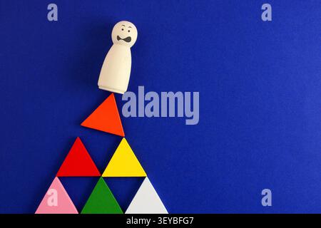 Person trying not to fall from a structure made of colorful triangles Stock Photo