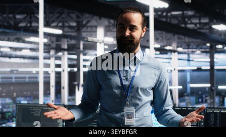 Data center manager presents AI technology and server room hardware during a data center demonstration. Stock Photo