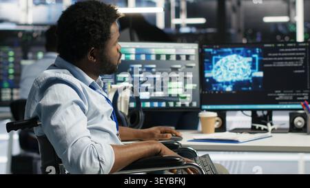 Worker using a wheelchair operates AI node tree software in a data center to monitor performance data. Stock Photo